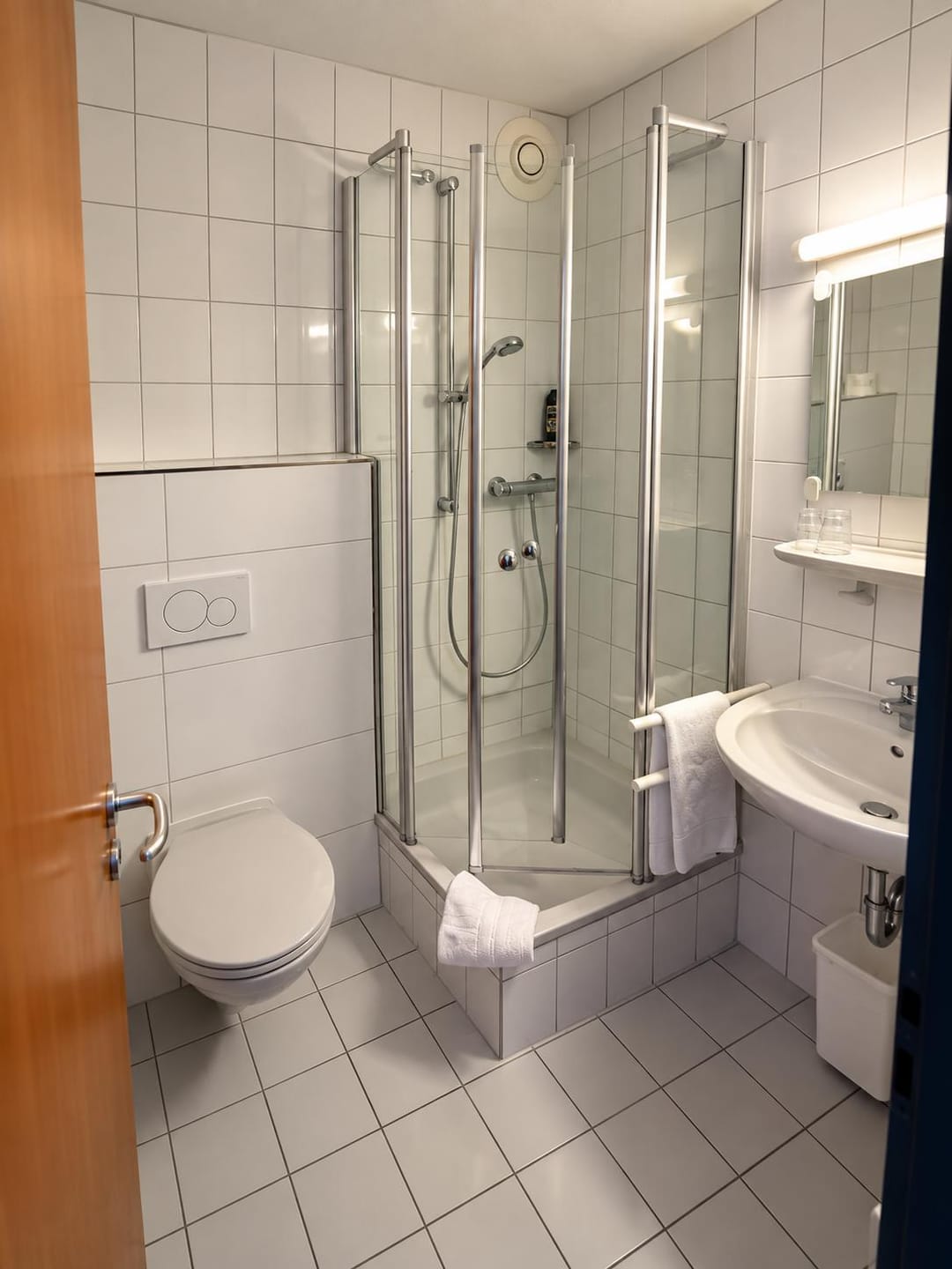 Badezimmer mit Dusche, WC und Waschbecken im Inteck Hotel